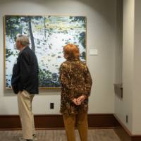Two people looking at pieces of art on gallery wall